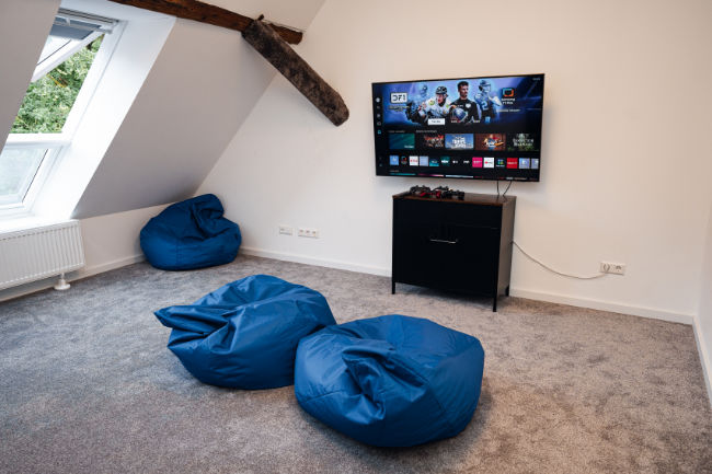 PS5 Konsole Bereich, Fernseher an der Wand und Sitzsäcke
