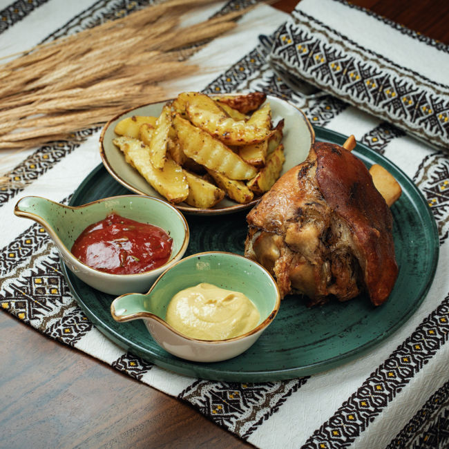 schweinshaxe mit Beilage und Sousse auf dem Teller