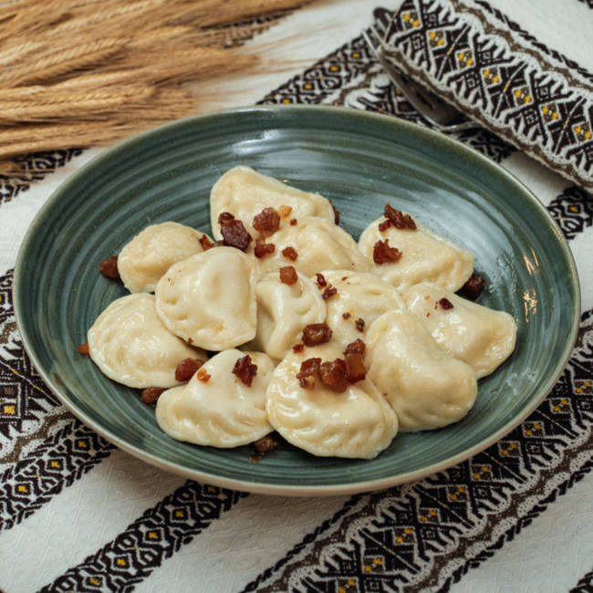 Teigtaschen mit Kartoffelfüllung dazu Schmand und Schweinegrieben mit Zwiebeln