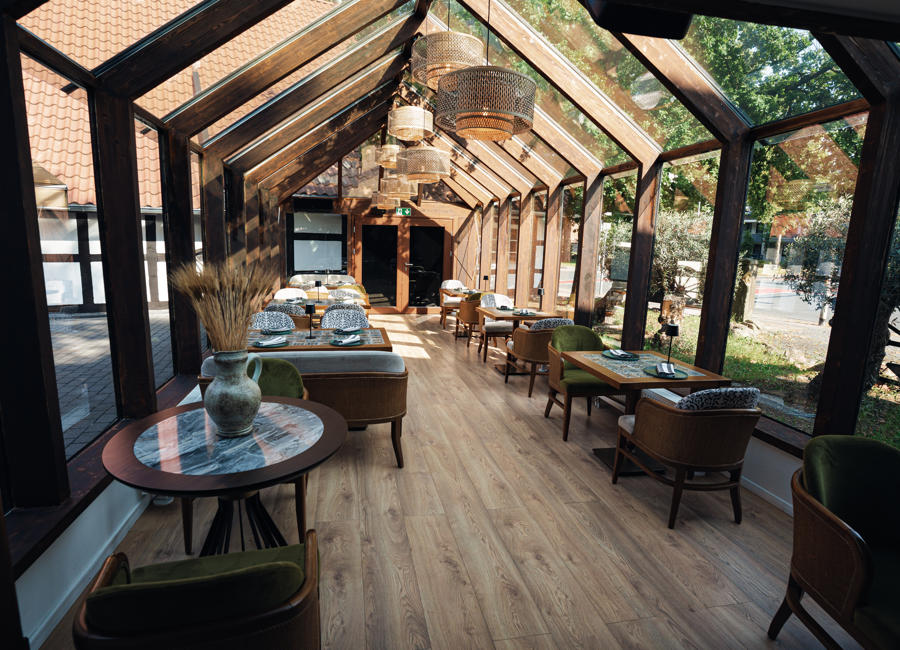 Wintergarten mit Tischen und Stühlen für Gäste